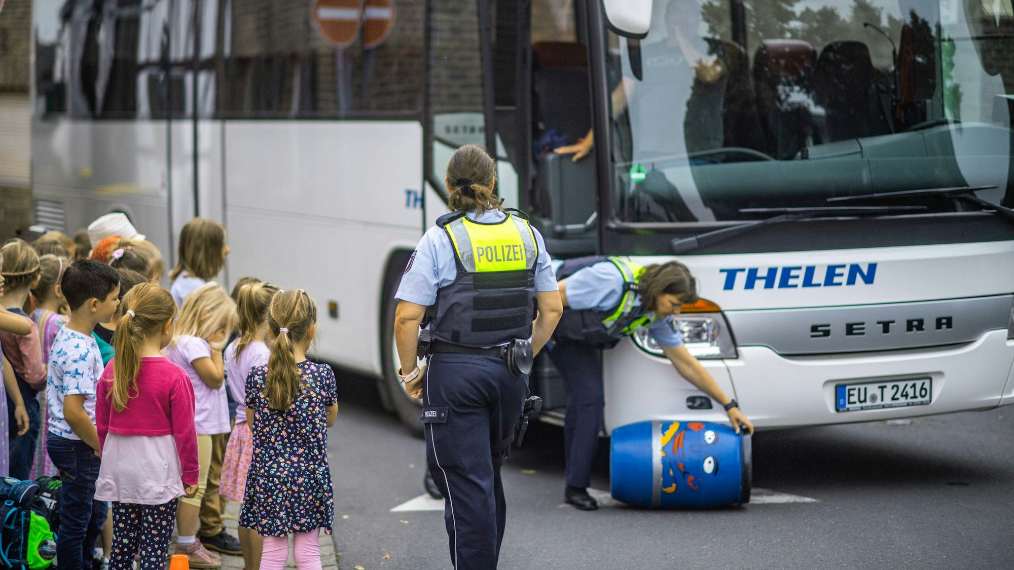 Das Bild zeigt zwei Polizistinnen und eine Gruppe von Grundschülern.