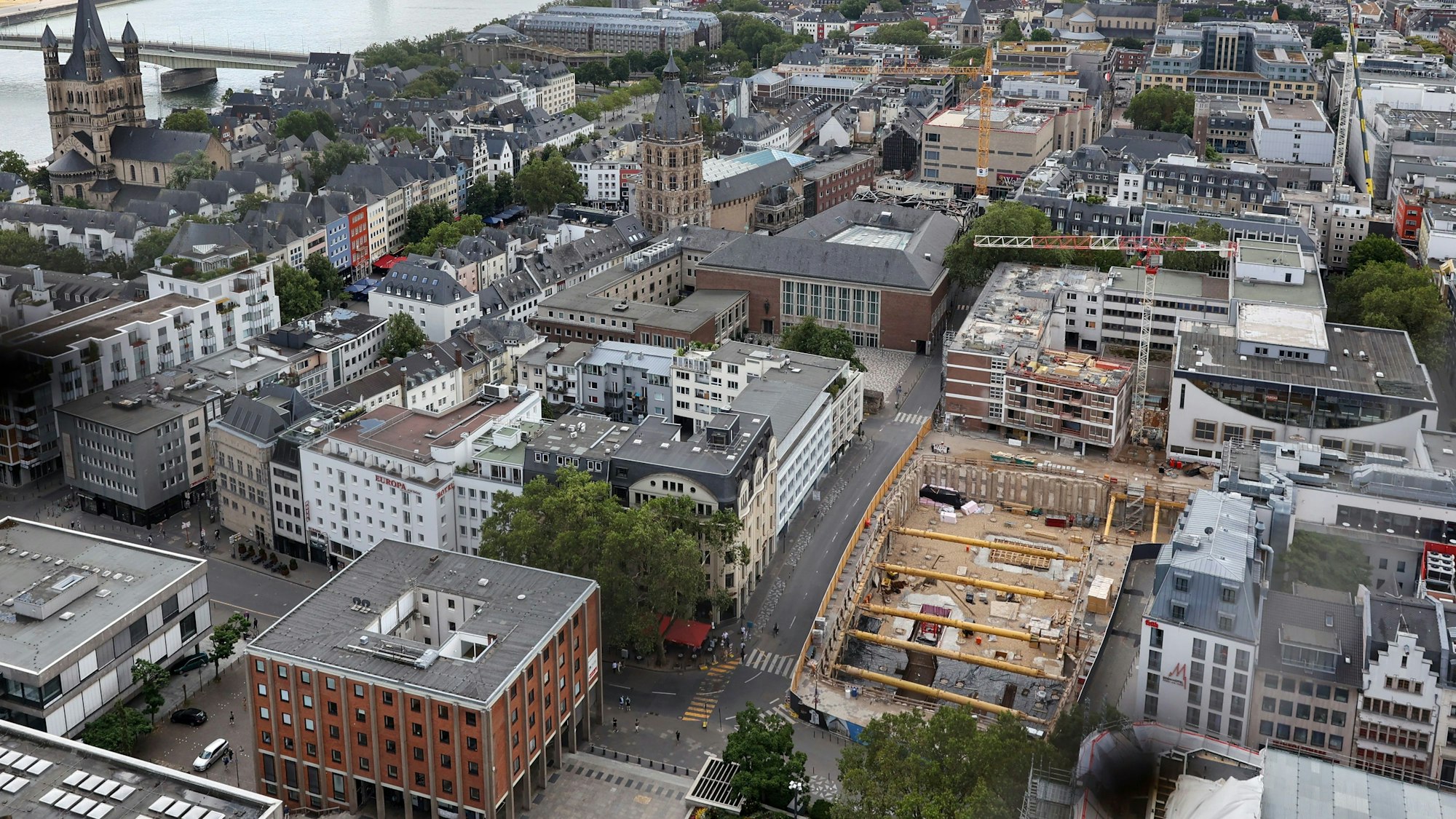Von oben: Die Baugrube ist Teil des nördlichen Baufeldes, der Kran dahinter gehört zum südlichen Baufeld. Im Vordergrund links ist das Kurienhaus der Kirche auf dem Roncalliplatz zu sehen.