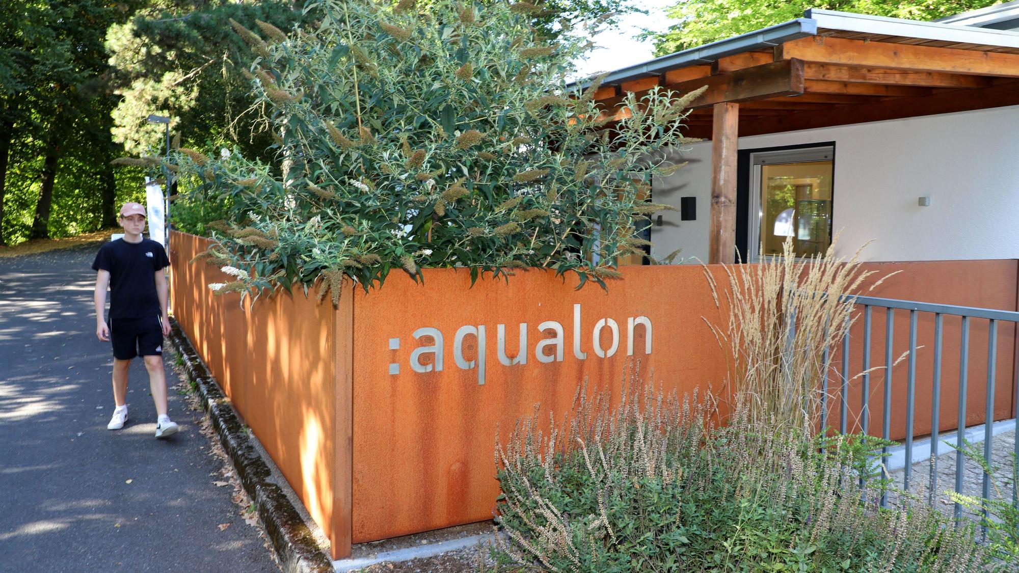 Ein Jugendlicher geht an einem Gebäude vorbei mit der Aufschrift „Aqualon“.