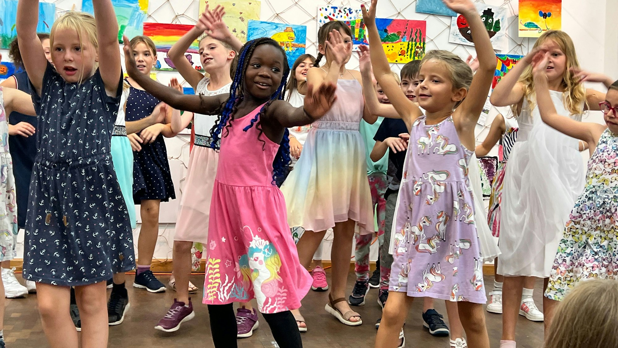Kinder tanzen vor bunten Bildern.