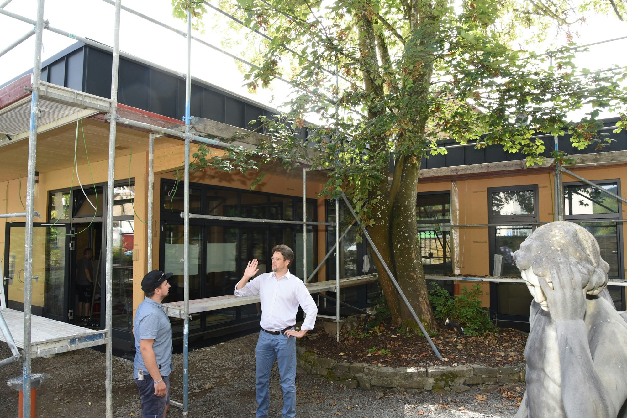 Im Engelgarten des Engel-Museums in Engelskirchen besprechen Baulaiter Tim Rother und Lukas Schlichtebrede vom Trägerverein die Baufortschritte, rechts im Bild ist der bekannte Meinardus-Engel aus Düsseldorf zu sehen.