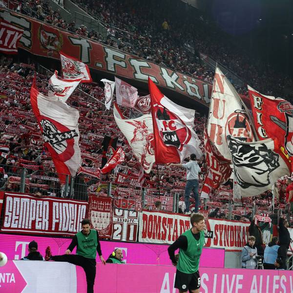 Auf einer Tribüne halten Fußball-Fans rot-weiße Schals hoch und schwenken Fahnen.