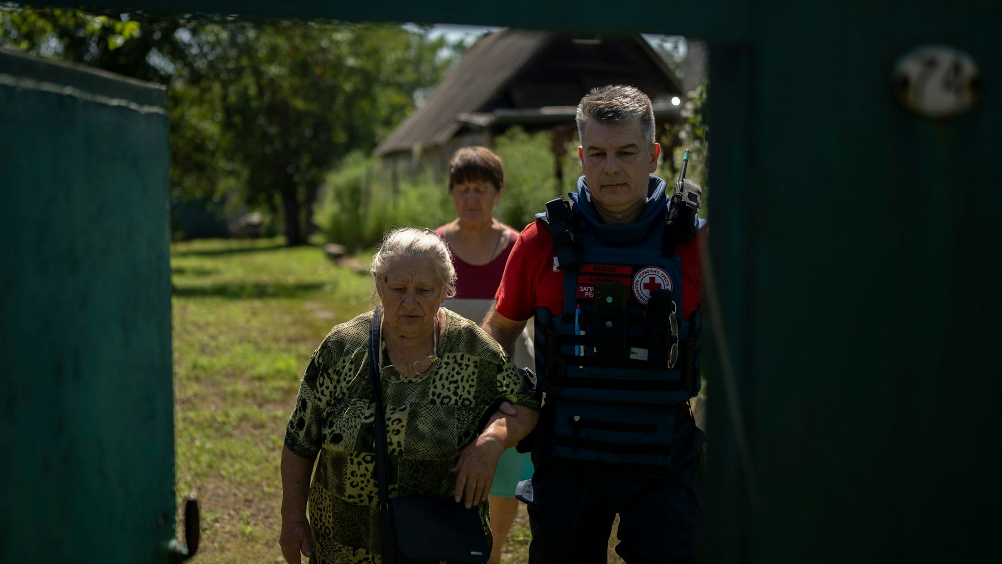 Ein Freiwilliger des Ukrainischen Roten Kreuzes hilft einer Bewohnerin im Rahmen einer Evakuierung am 14. August in ein Auto.