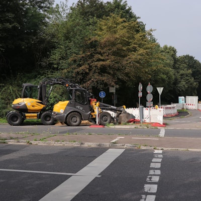 Auf einer Straße stehen Baken und Baumaschinen.