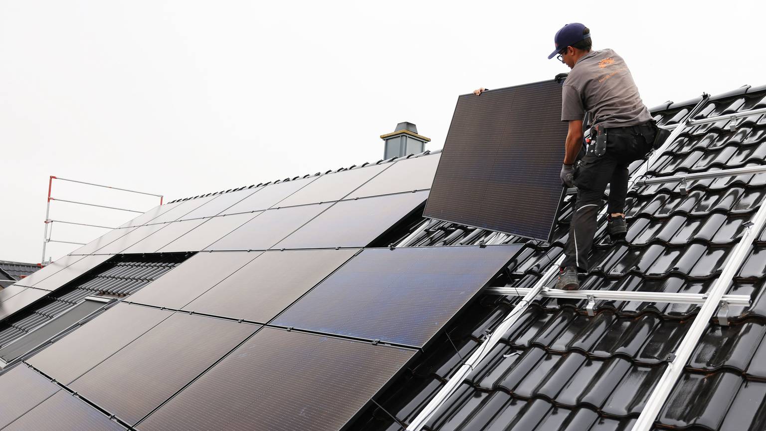 Handwerker montieren auf dem Dach eines Wohnhauses Solarmodule. +++ dpa-Bildfunk +++
