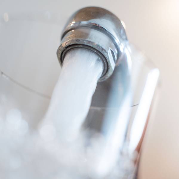 Wasser läuft aus einem Wasserhahn in ein Glas.