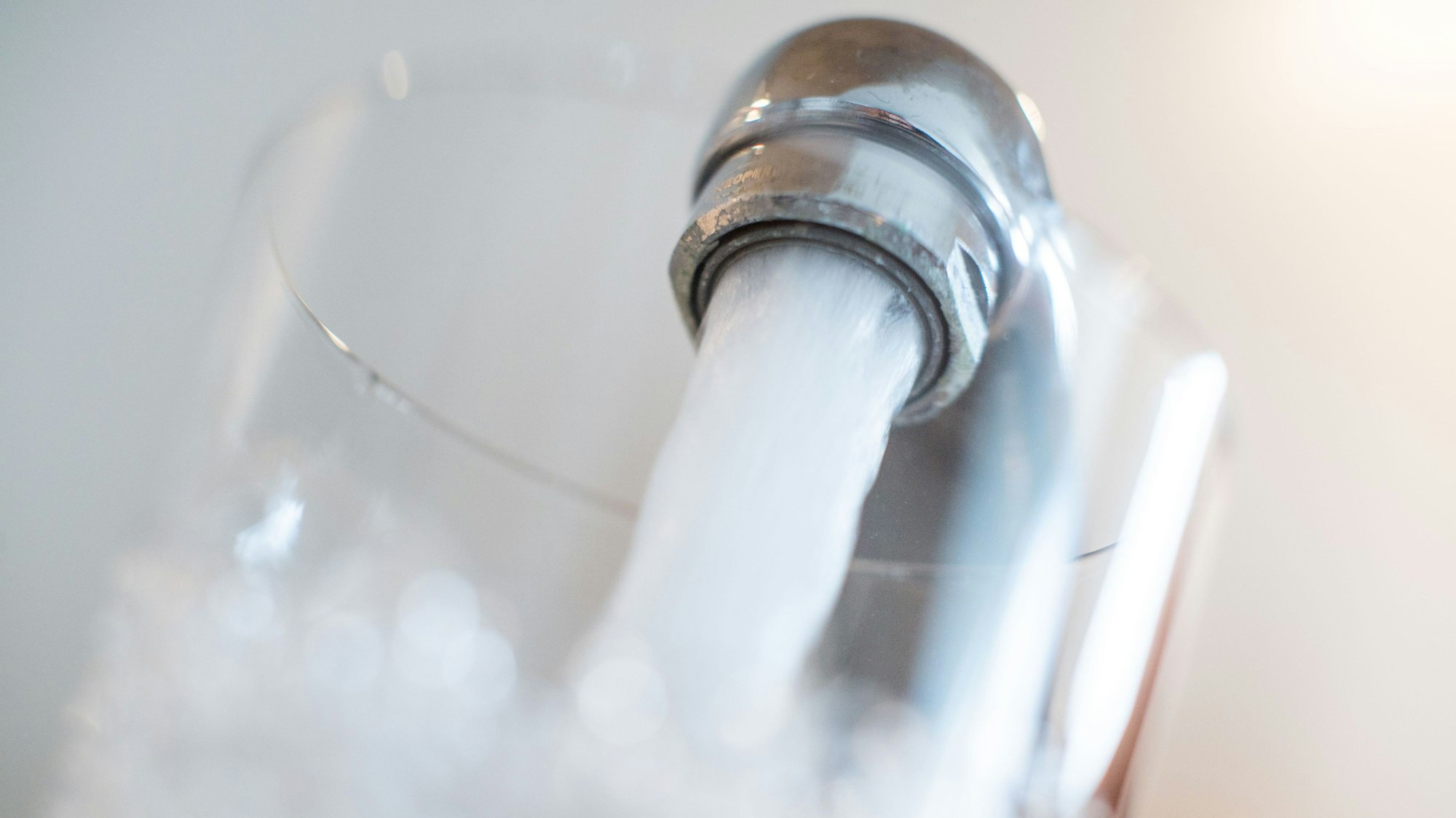 Wasser läuft aus einem Wasserhahn in ein Glas.