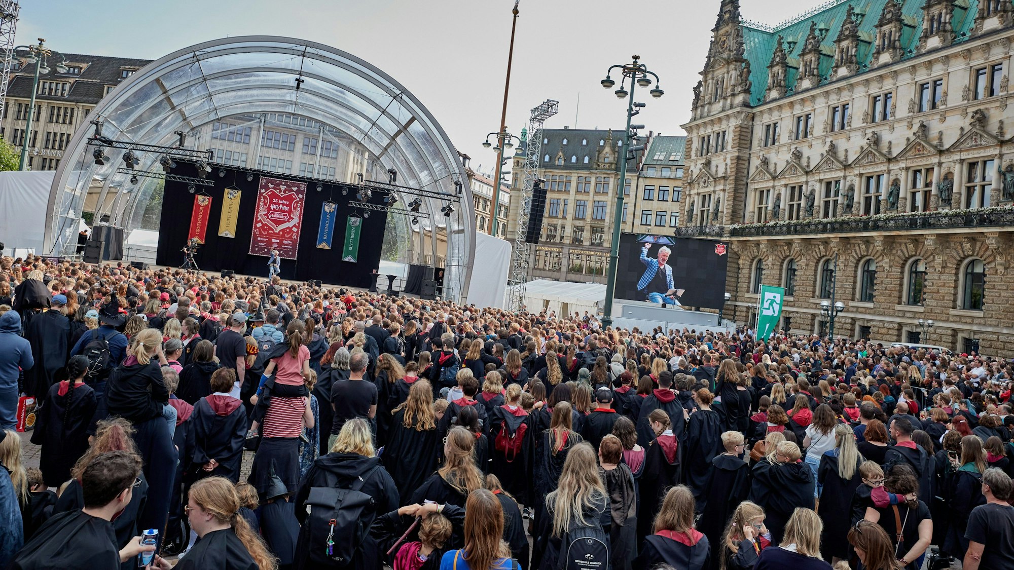 Rufus Beck, Schauspieler, liest auf der Bühne am Rathausmarkt aus Harry Potter. Vor der Bühne stehen über 1000 Menschen als Harry Potter verkleidet mit Umhängen in schwarz-rot.
