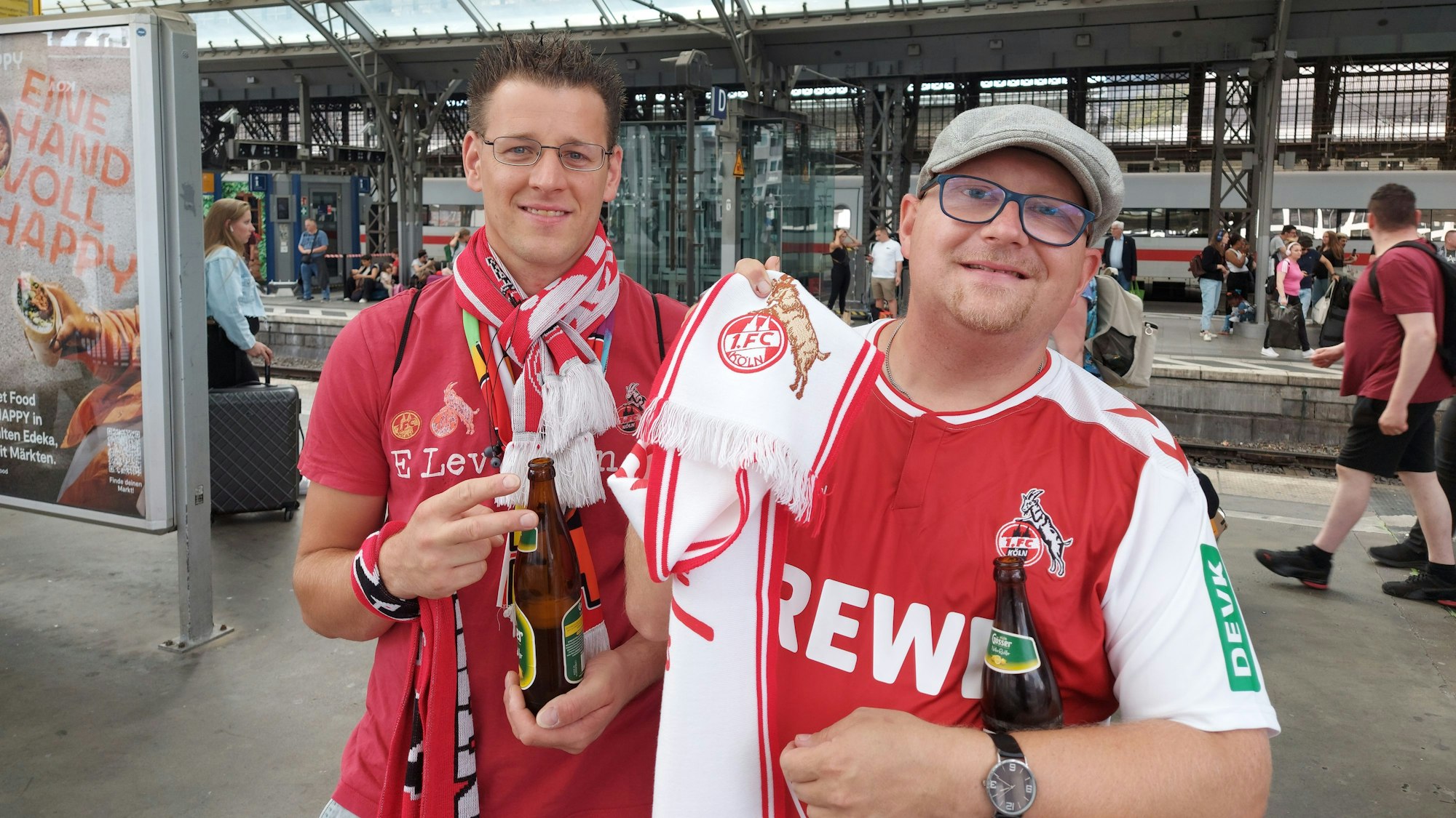 Kai und Denis in FC-Trikots und Schals am Kölner Hauptbahnhof.