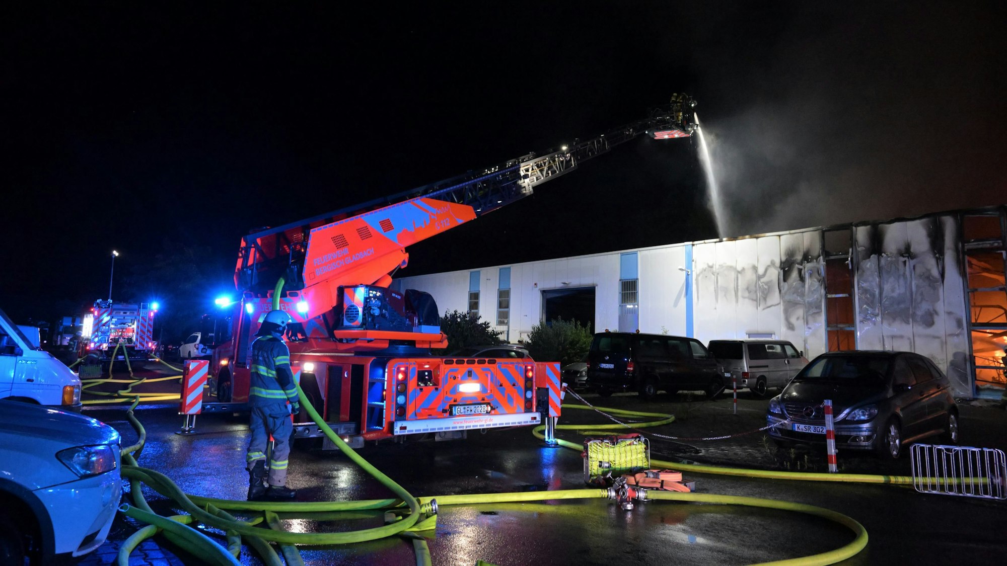 Von einer Drehleiter wird ein Brand in einer Lagerhalle mit Löschwasser bekämpft.
