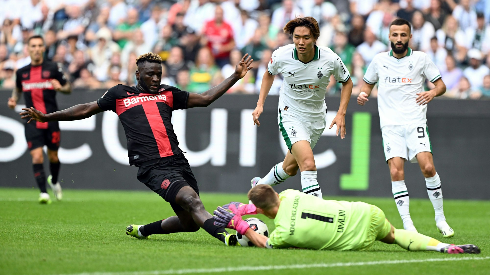 Mönchengladbachs Torhüter Jonas Omlin (r) und Leverkusens Victor Boniface kämpfen um den Ball.