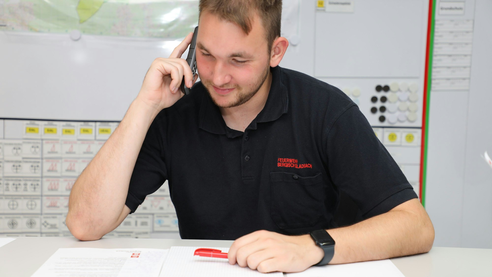 Ein Mitglied der Unterstützungseinheit der Feuerwehr Bergisch Gladbach telefoniert in einem Leitstellenraum.
