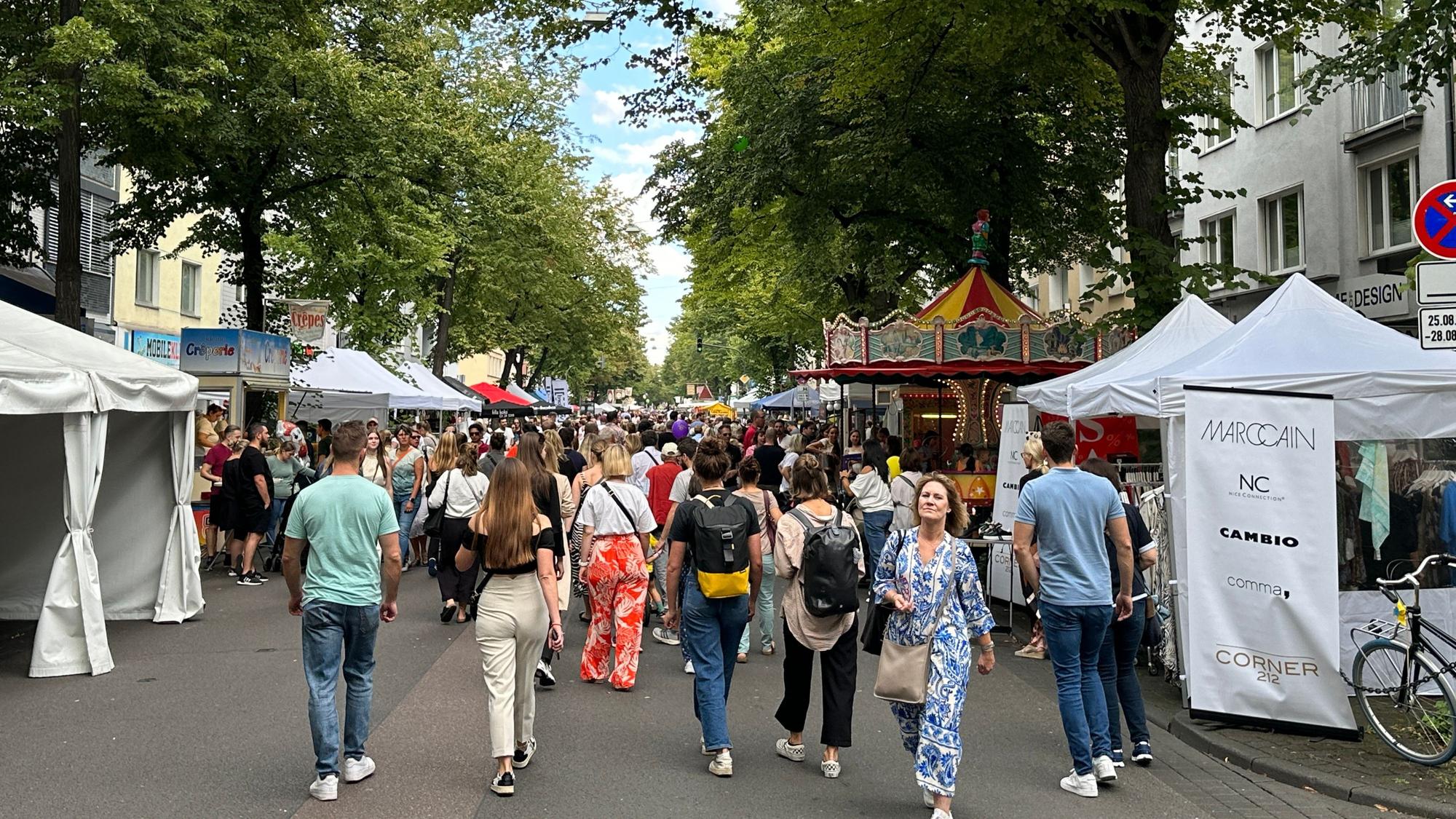 Menschen flanieren zwischen Ständen.