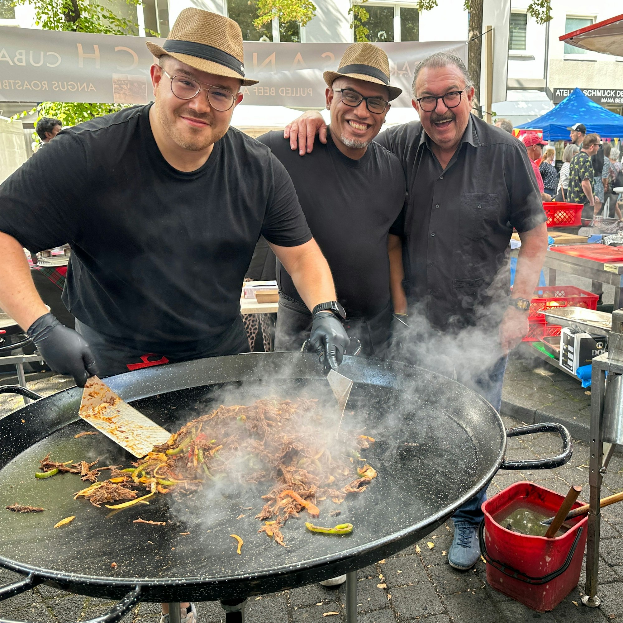 Drei Männer an einer großen Grillpfanne