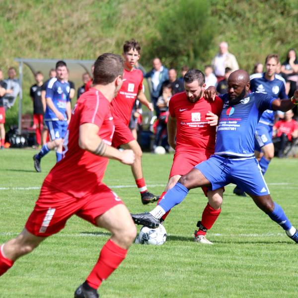 Zwei Spieler im Zweikampf um den Ball. Im Hintergrund sind die Zuschauer zu sehen.