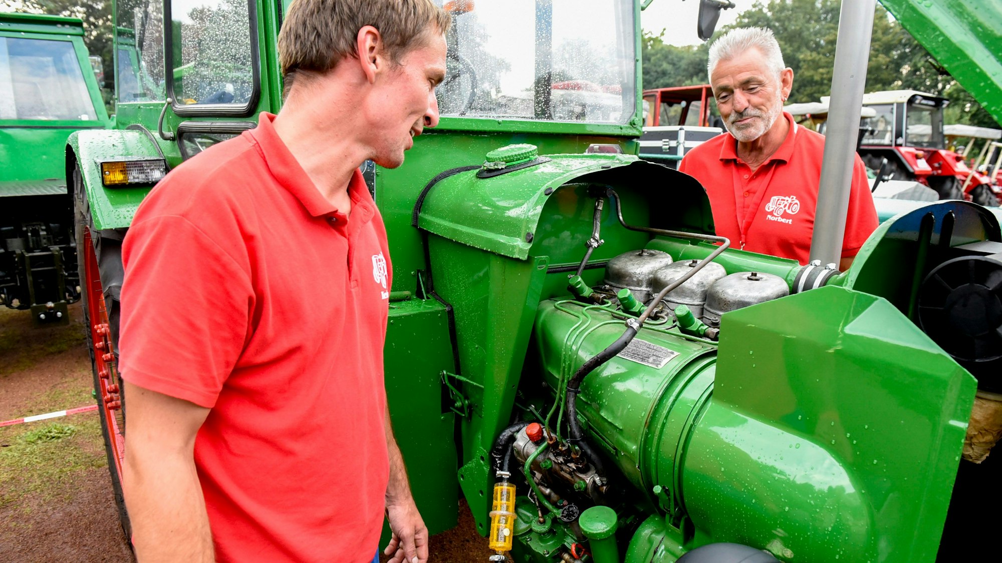 Das Foto zeigt Kevin Abs und Norbert Schlömer vor einem grünen Traktor der Marke Deutz.