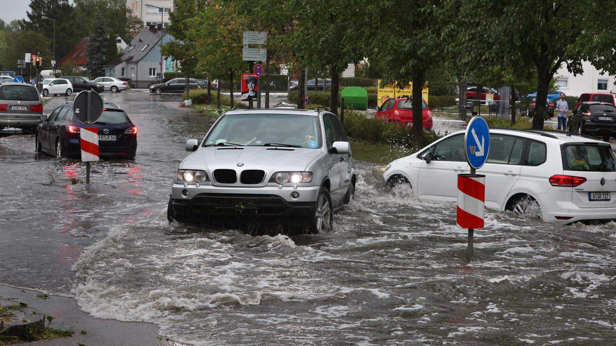 Autos fahren auf einer überfluteten Straße.