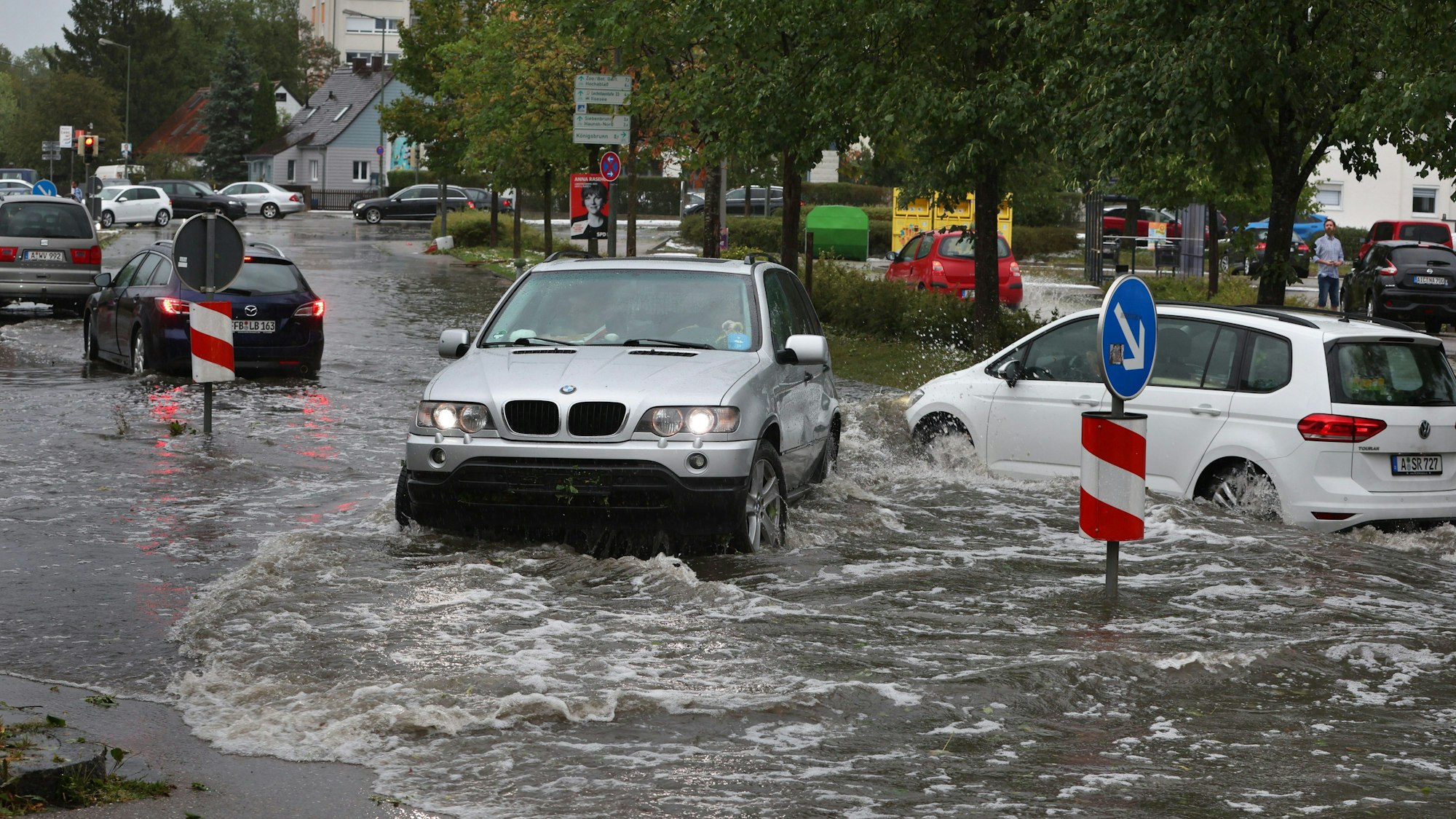 Autos fahren auf einer überfluteten Straße.