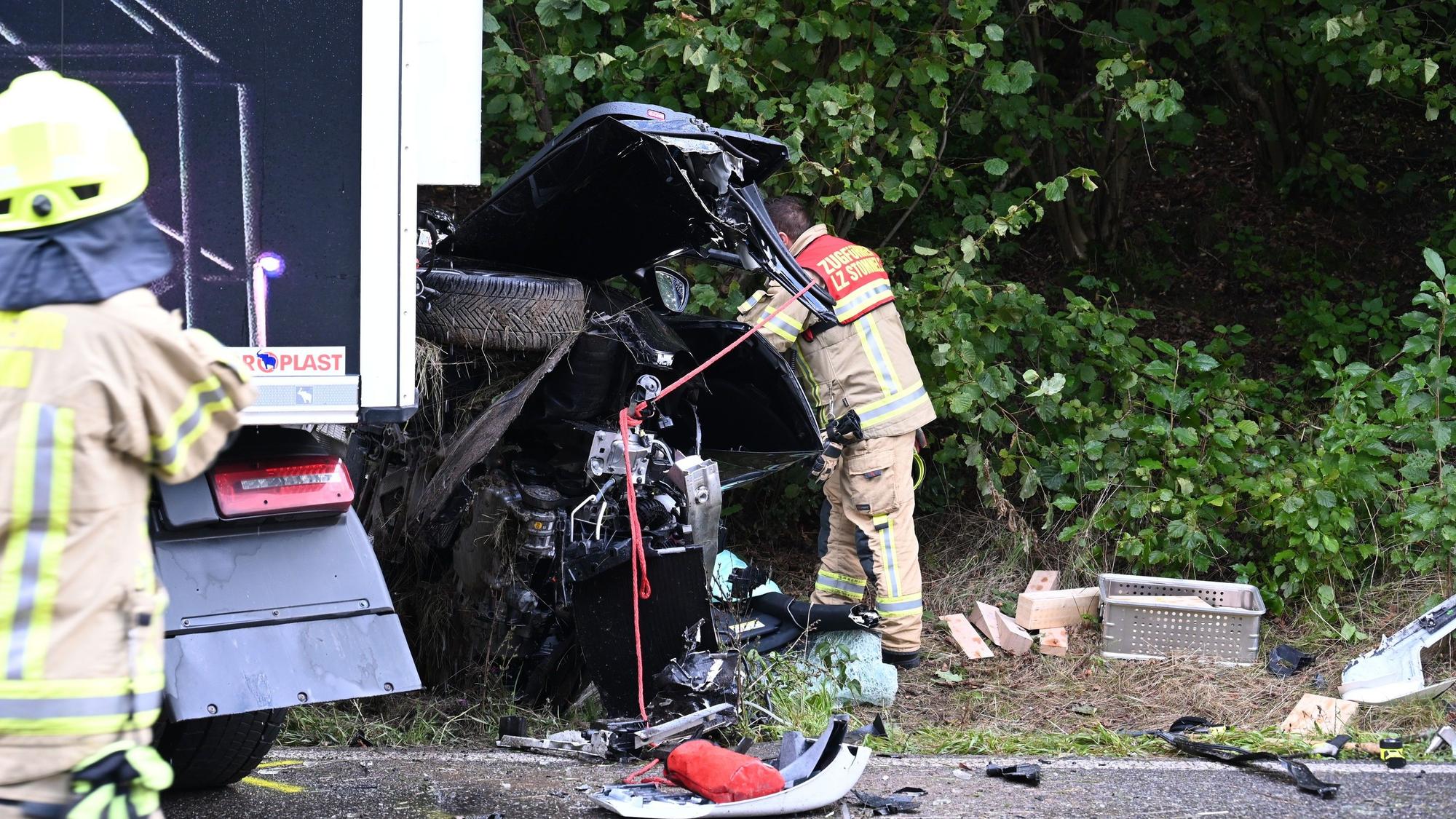 Ein Feuerwehrmann steht nach dem tödlichen Unfall in Pulheim vor dem völlig zerstörten Autowrack.