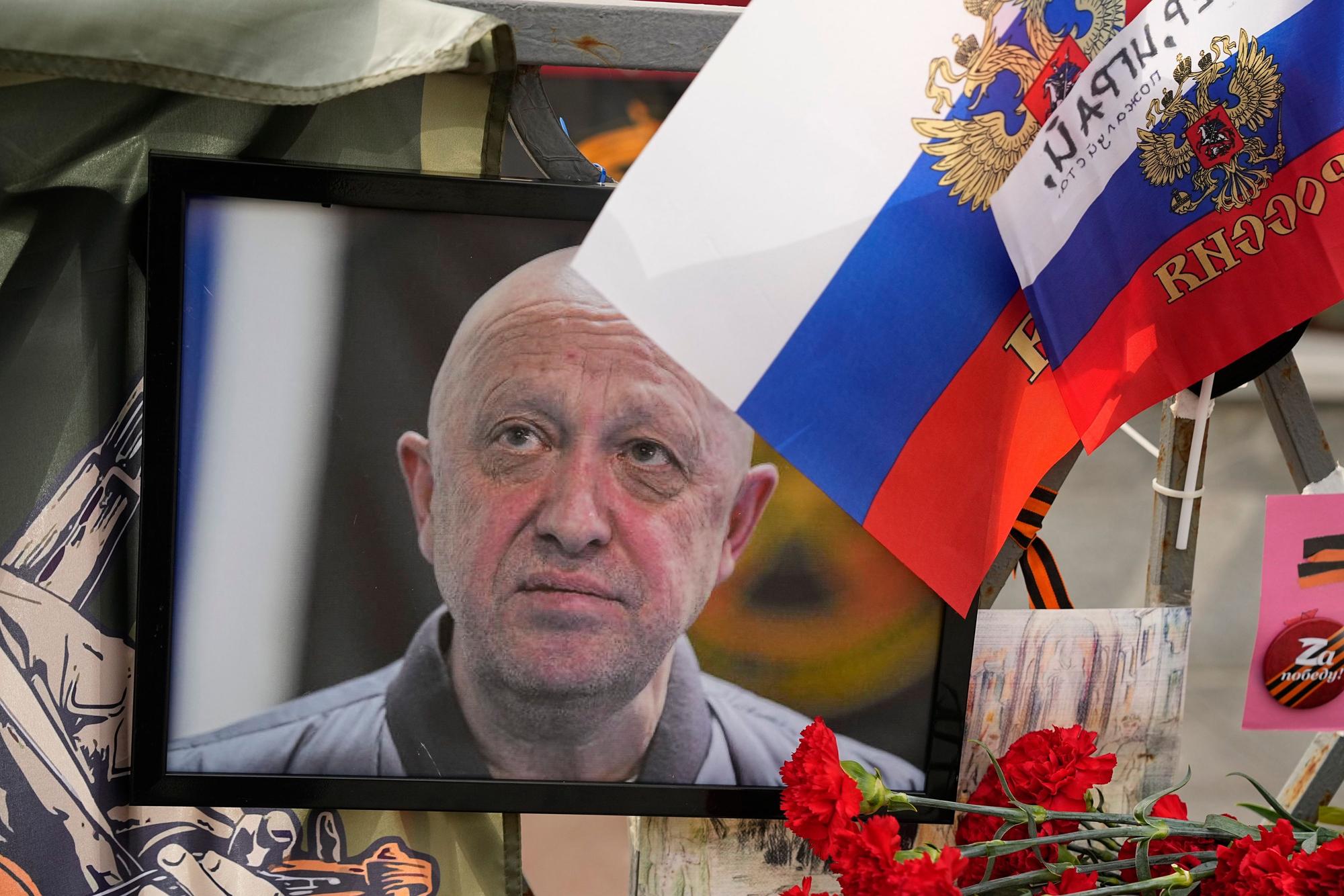 26.08.2023, Russland, Moskau: Ein Porträt des russischen Söldnerführers Jewgeni Prigoschin steht an einer informellen Gedenkstelle in der Nähe des Kremls. Zwei Tage nach dem mutmaßlichen Tod des russischen Söldnerführers Jewgeni Prigoschin bei einem Flugzeugabsturz sind die Flugschreiber und Trümmer der Maschine zu Untersuchungen abtransportiert worden. An der Absturzstelle seien zehn Leichen gefunden worden, die Identität der Toten werde nun anhand molekular-genetischer Analysen geklärt, teilten die Ermittler in Moskau am Freitagabend (25.08.2023) mit. Foto: Alexander Zemlianichenko/AP/dpa +++ dpa-Bildfunk +++