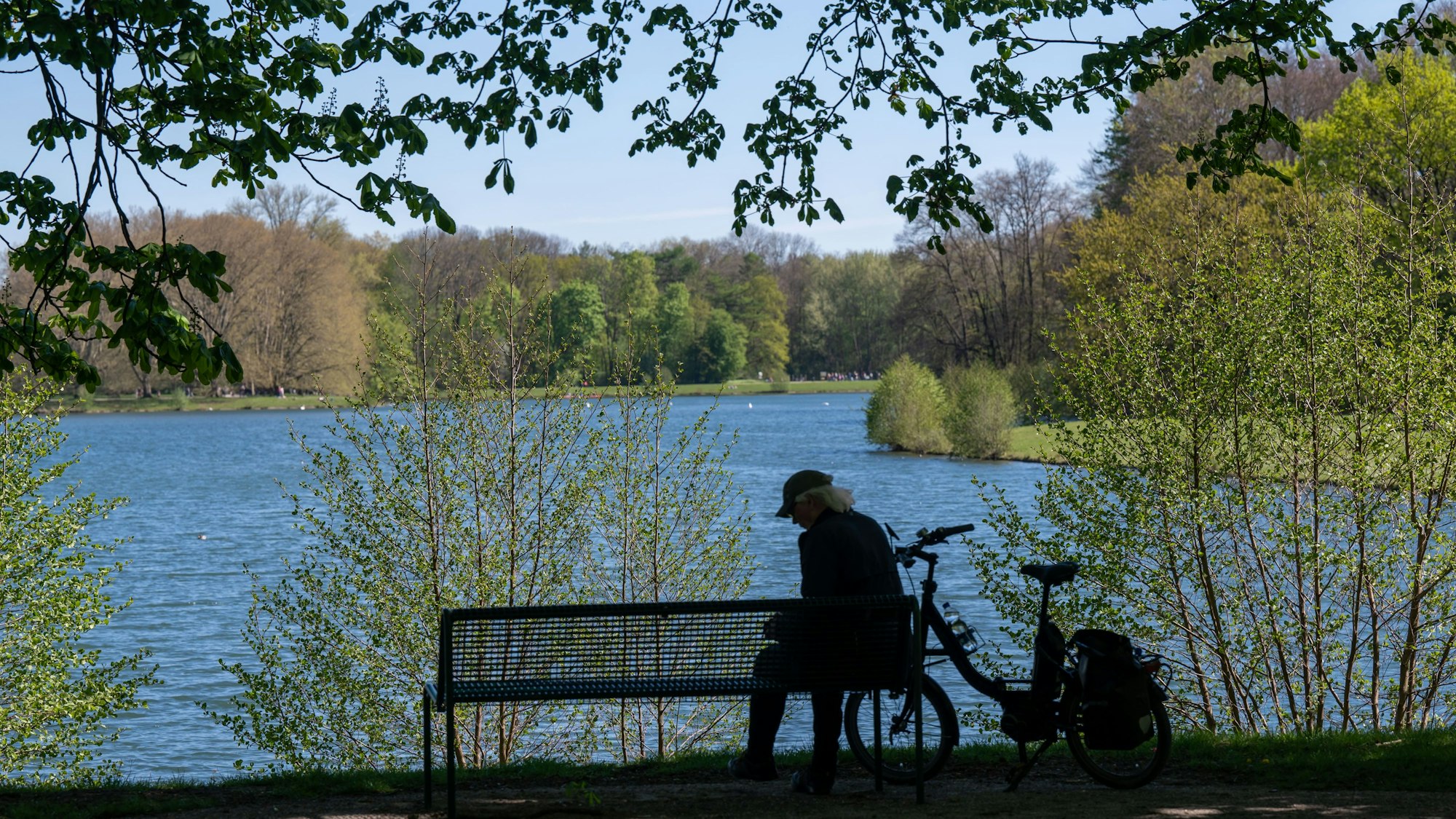 Mann sitzt auf einer Bank an einem Weiher