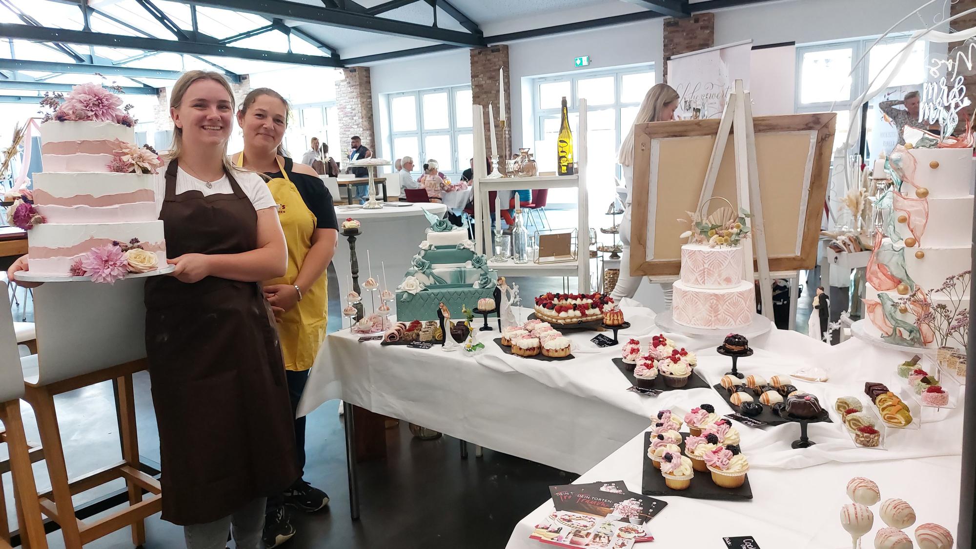 Konditorgesellin Sophie Funken (l.) und ihre Chefin Stephanie Schmidt-Eisenbach von Schmidt's Backstübchen zeigen Hochzeitstorten und Konditorwaren.