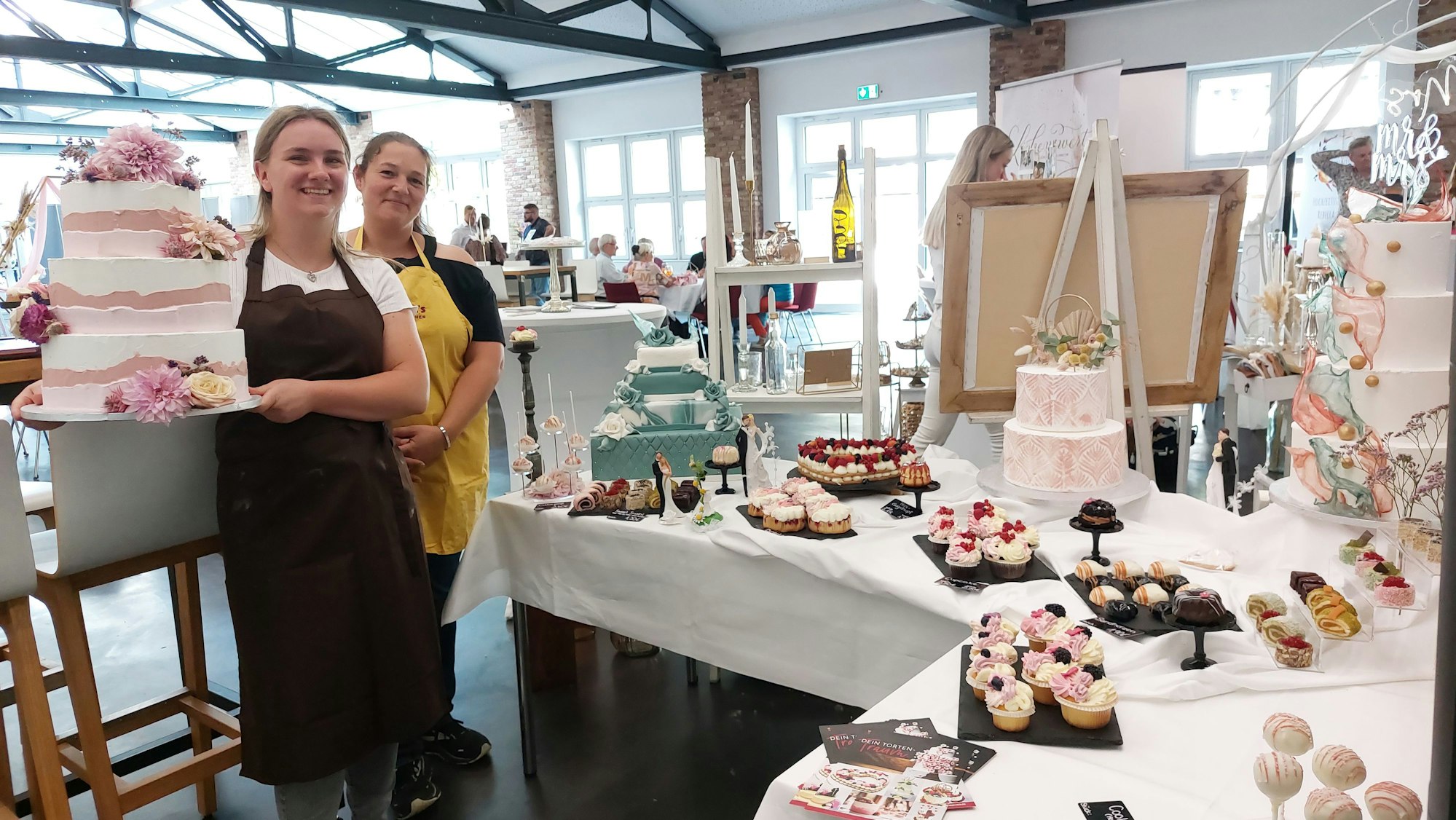 Konditorgesellin Sophie Funken (l.) und ihre Chefin Stephanie Schmidt-Eisenbach von Schmidt's Backstübchen zeigen Hochzeitstorten und Konditorwaren.