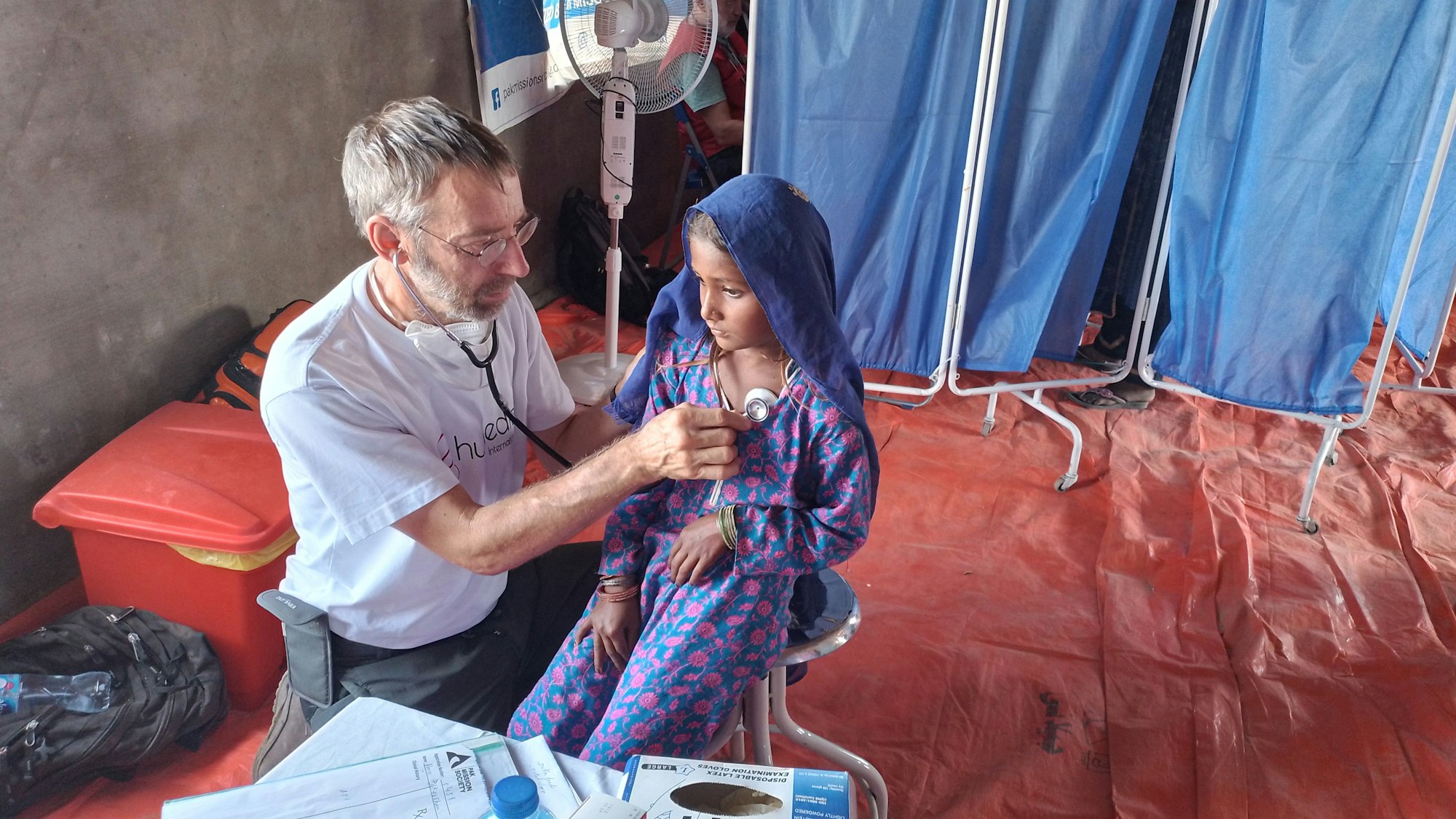 Der Niederkasseler Allgemeinmediziner Michael Brinkmann untersucht in einem Krankenhaus in Pakistan ein kleines Mädchen mit einem Stethoskop.