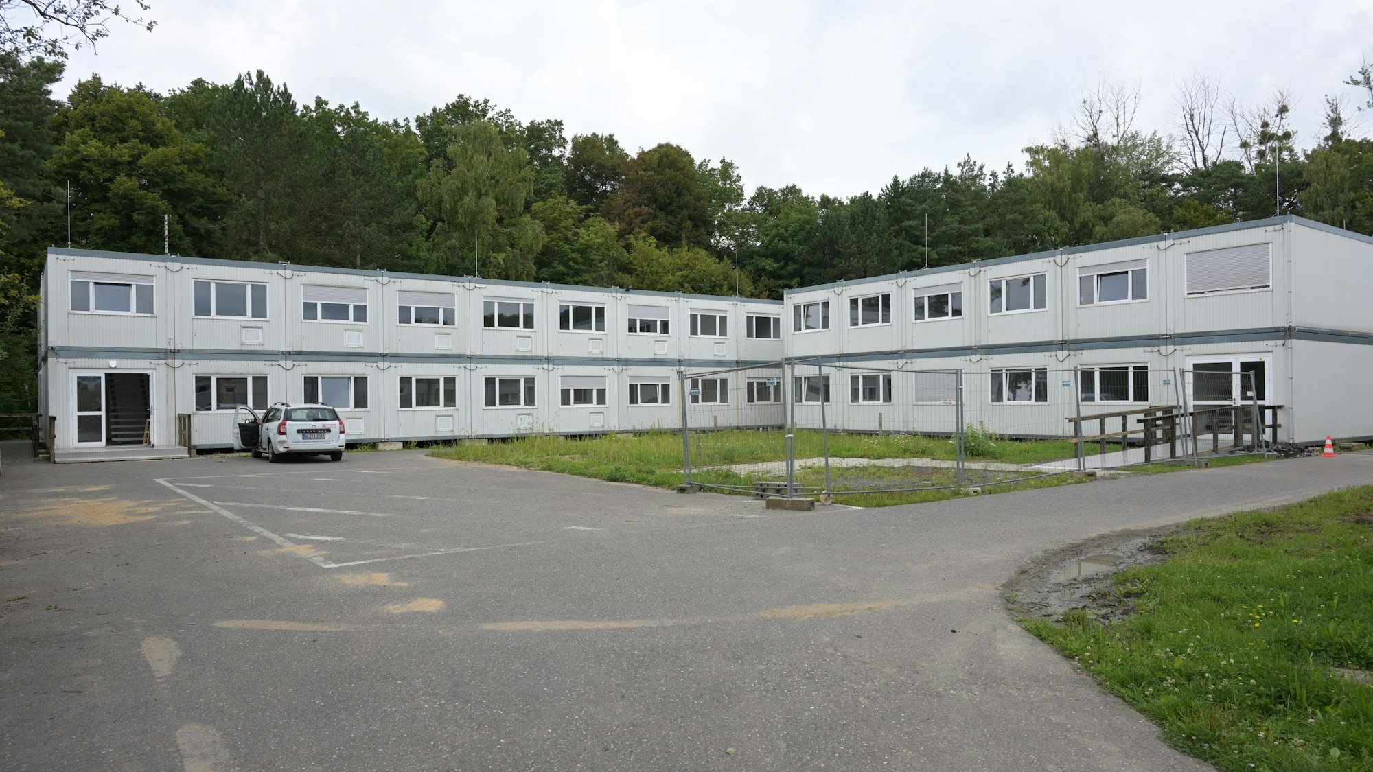 Man sieht zwei über Eck gebaute Riegel von grauen Containerbauten.