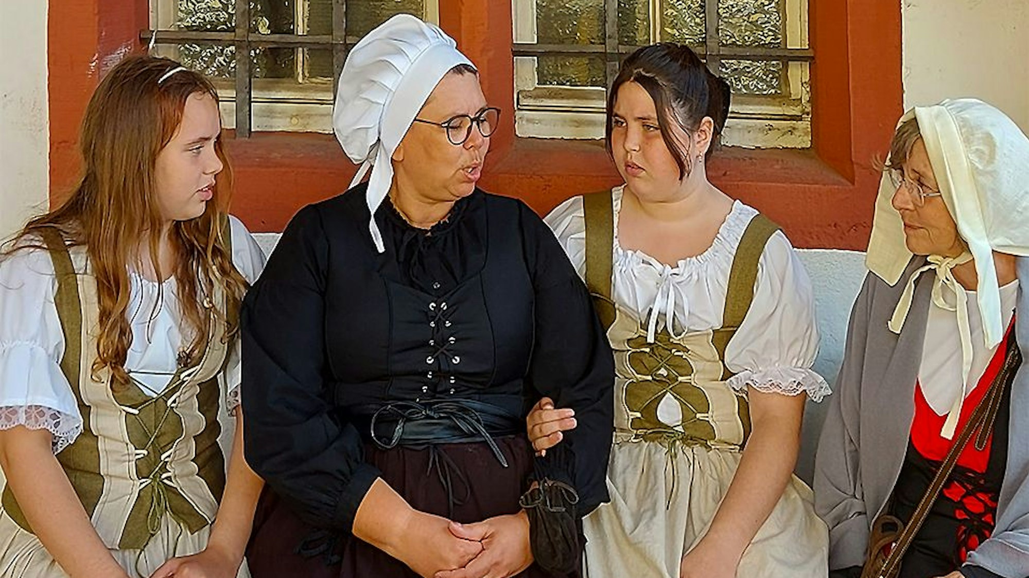 Vier als Marktfrauen in historische Kostüme gekleidete Frauen sitzen vor dem Rathaus in Bad Münstereifel.