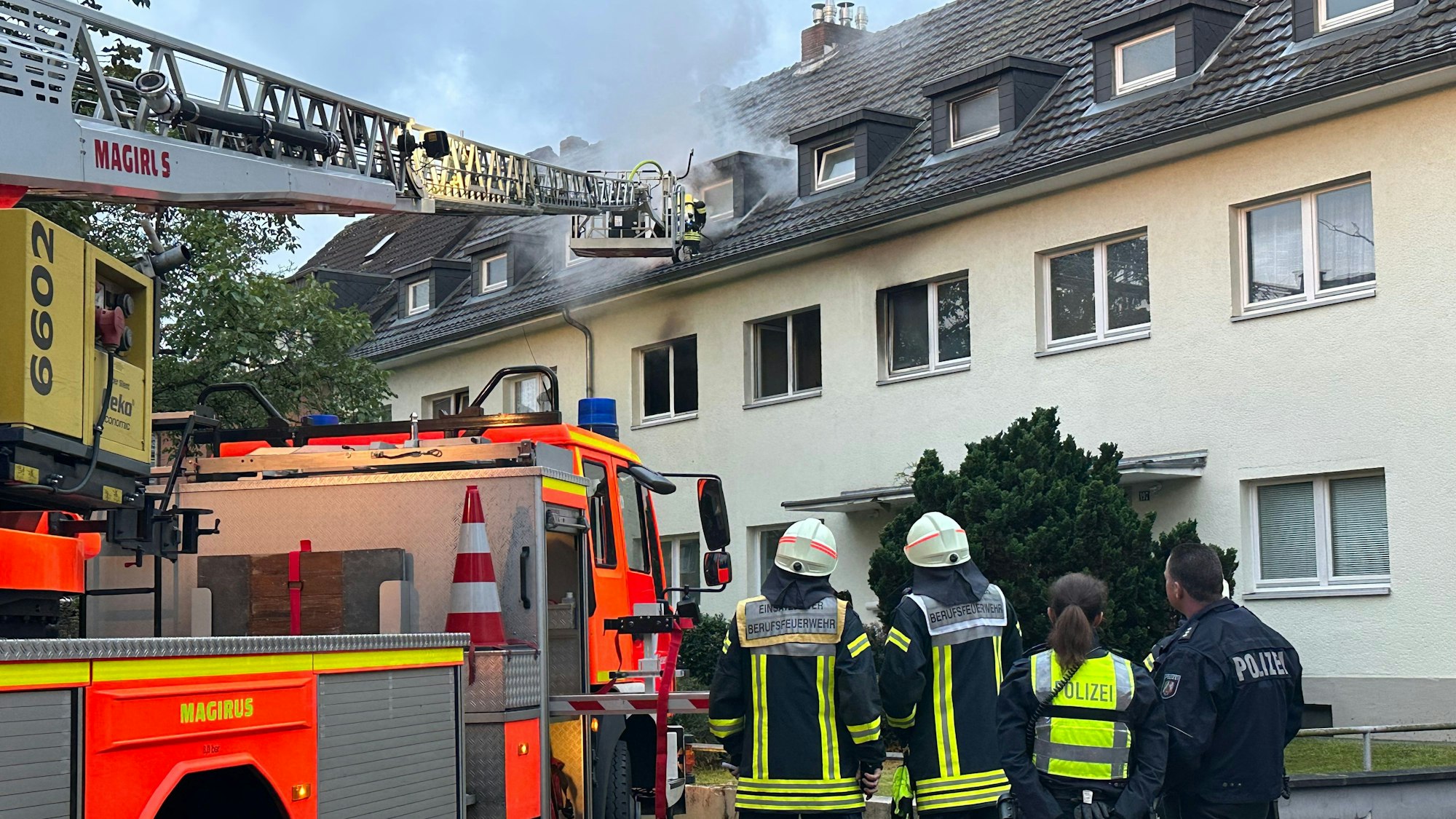 Ein Einsatzwagen und Beamte bei dem Brand in Dünnwald.