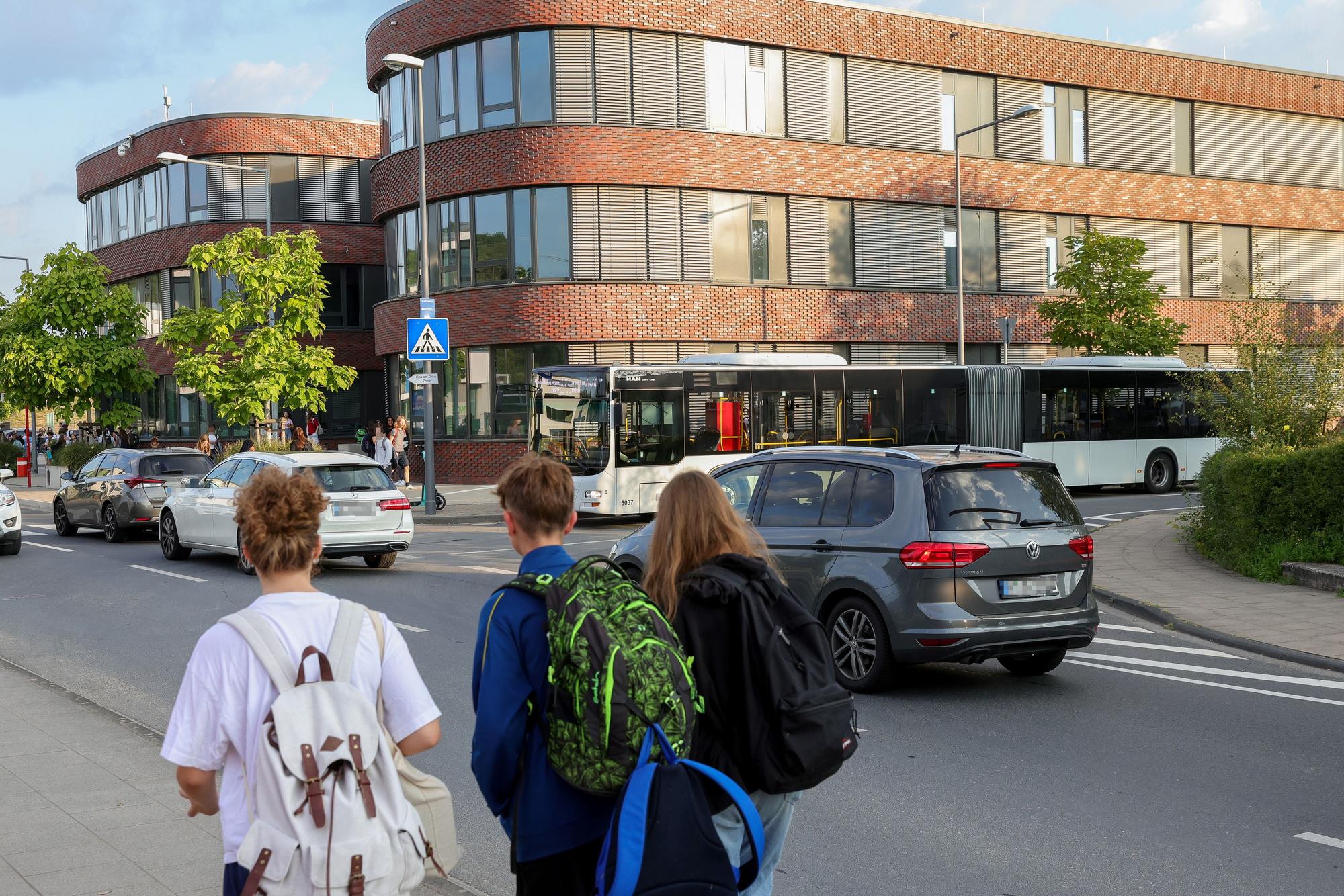 Kinder gehen eine Straße entlang, auf der Autos und ein Bus fahren.