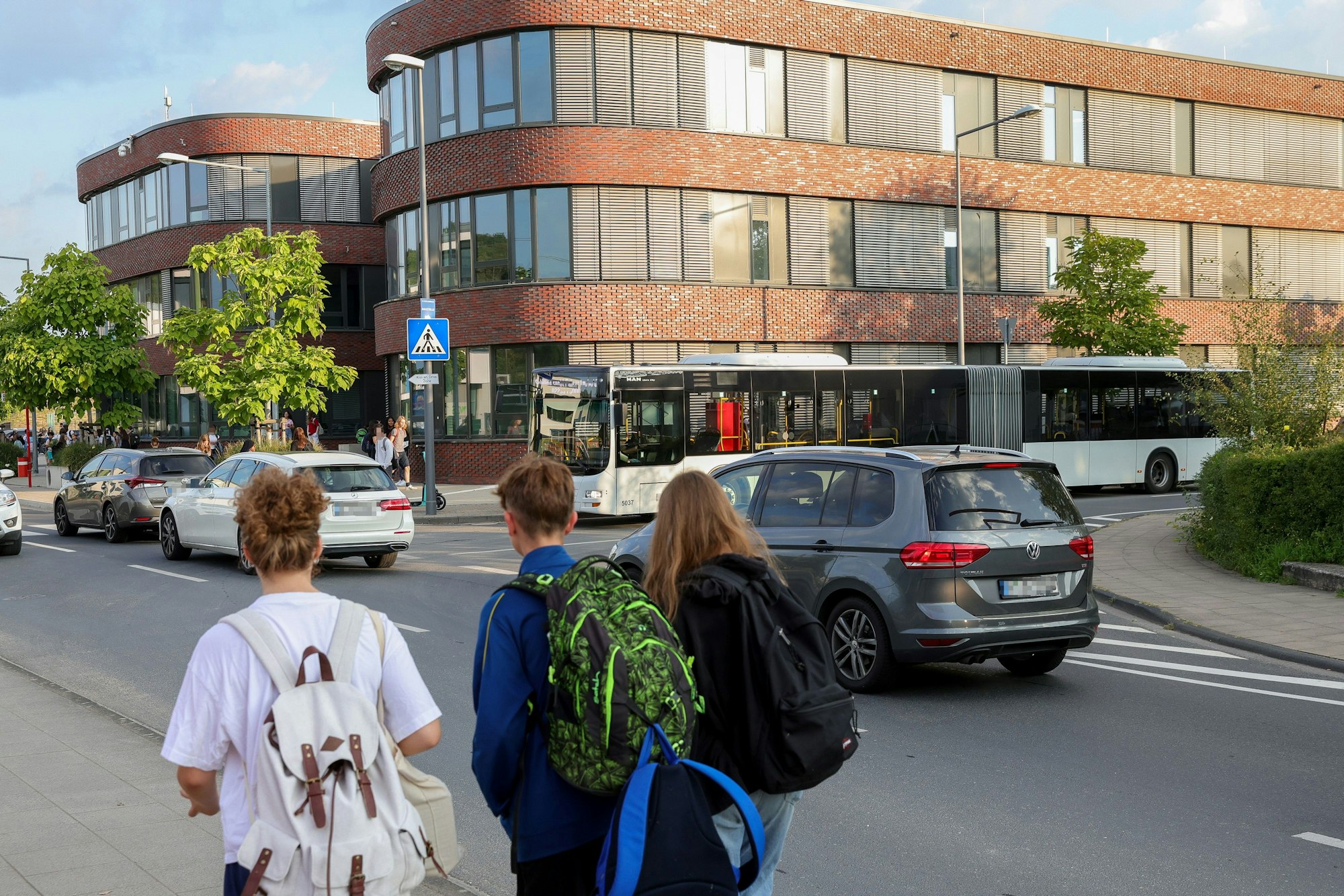 Kinder gehen eine Straße entlang, auf der Autos und ein Bus fahren.