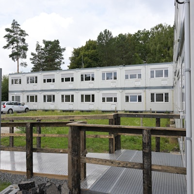 Zu sehen sind zwei Riegel der grauen zweigeschossigen Containerbauten.