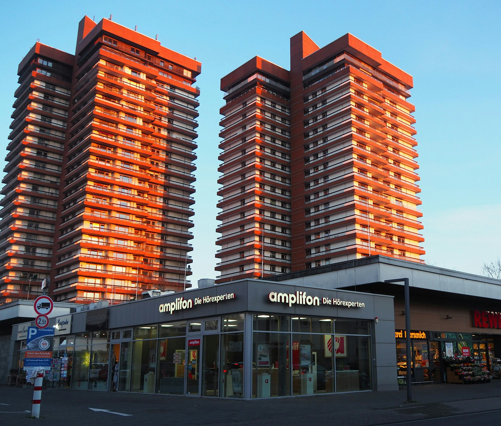 Vier Hochhäuser mit gelb-roter Fassade ragen in den blauen Himmel.
