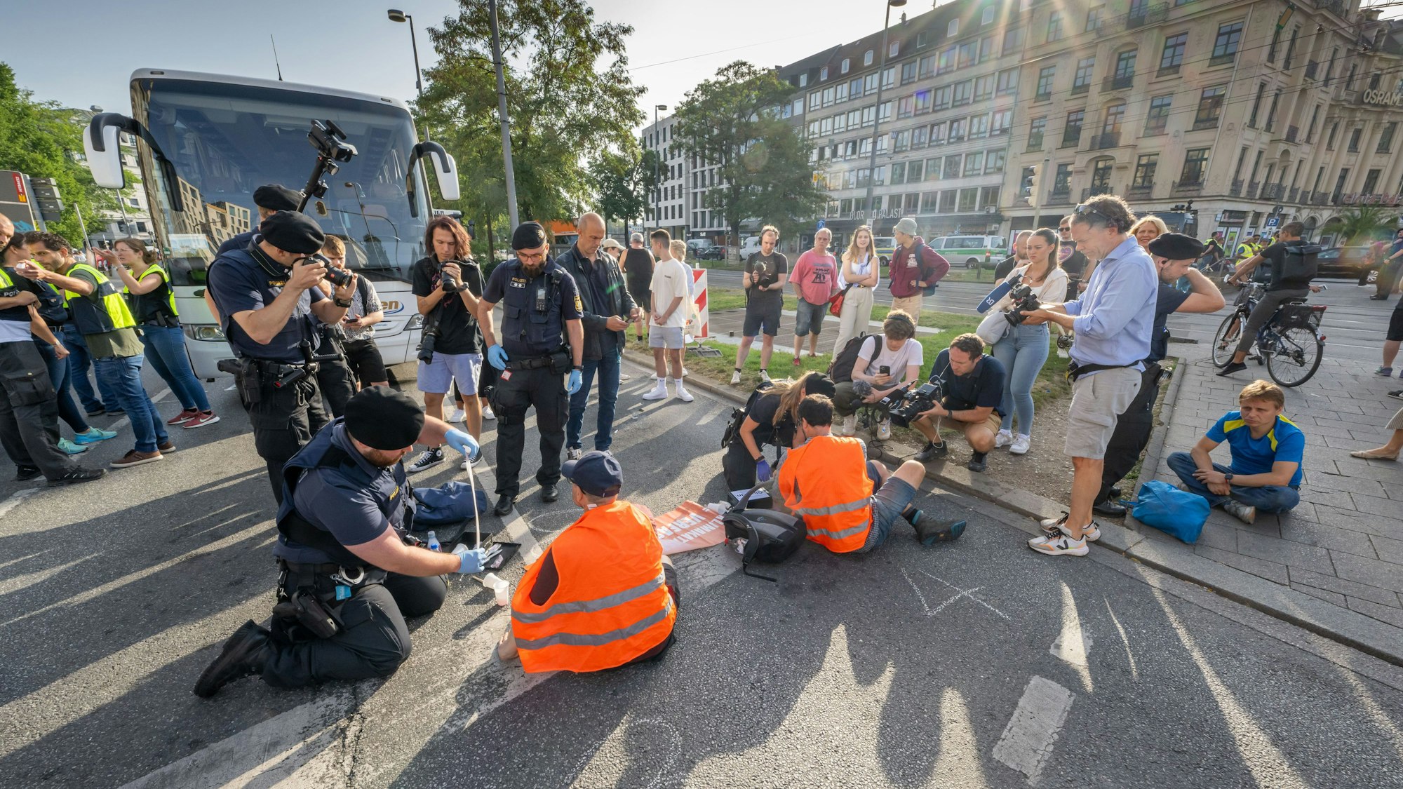 Polizisten versuchen auf der Kreuzung am Stachus in der Innenstadt Münchens Aktivisten der Letzten Generation vom Straßenbelag zu lösen.