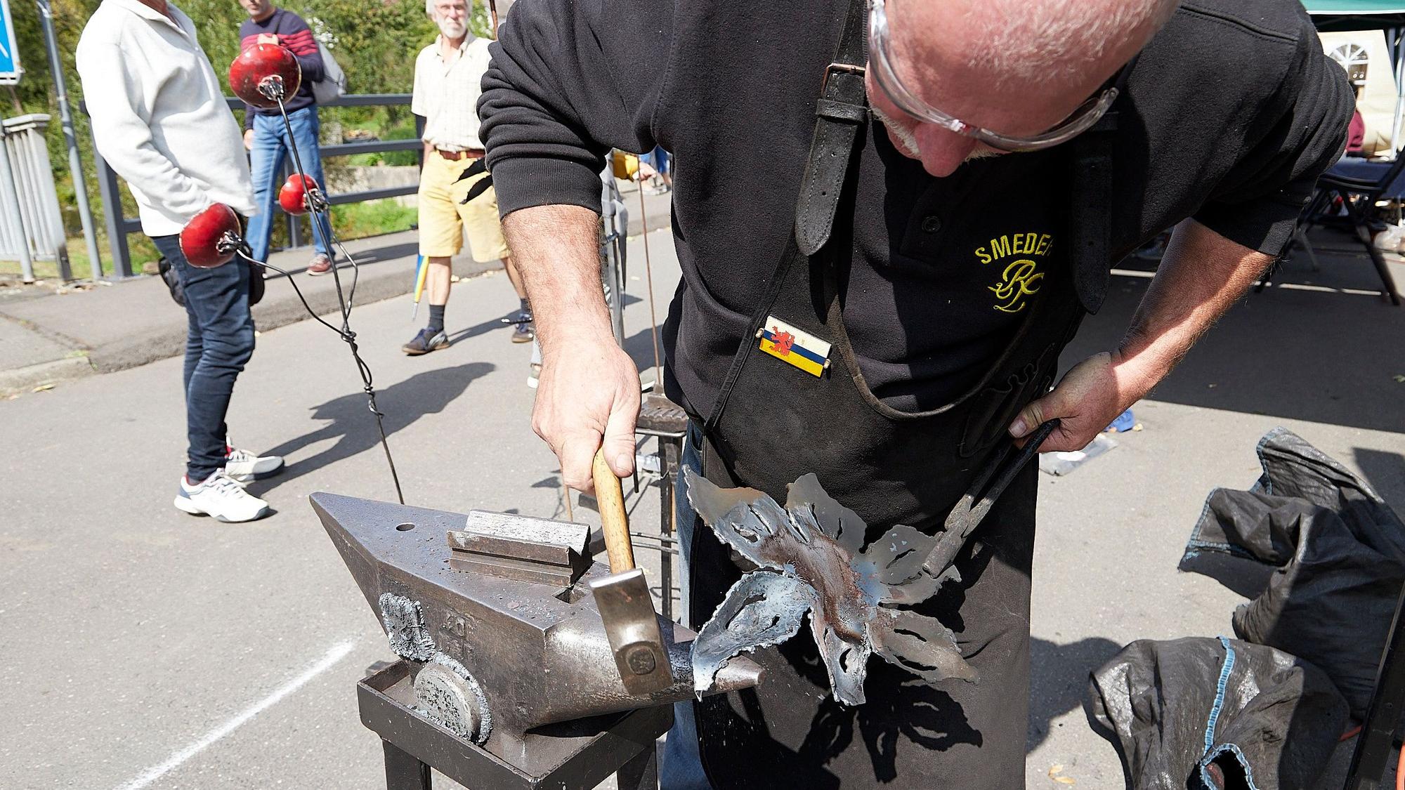Ein Mann bearbeitet Metall auf einem Amboss.