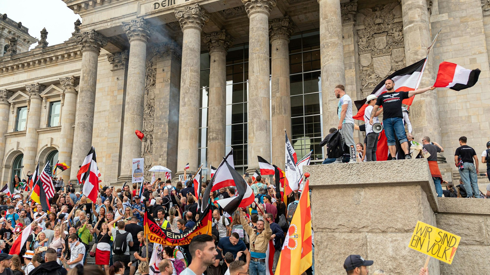 Berlin: Teilnehmer einer Kundgebung gegen die Corona-Maßnahmen stehen auf den Stufen zum Reichstagsgebäude, zahlreiche Reichsflaggen sind zu sehen.