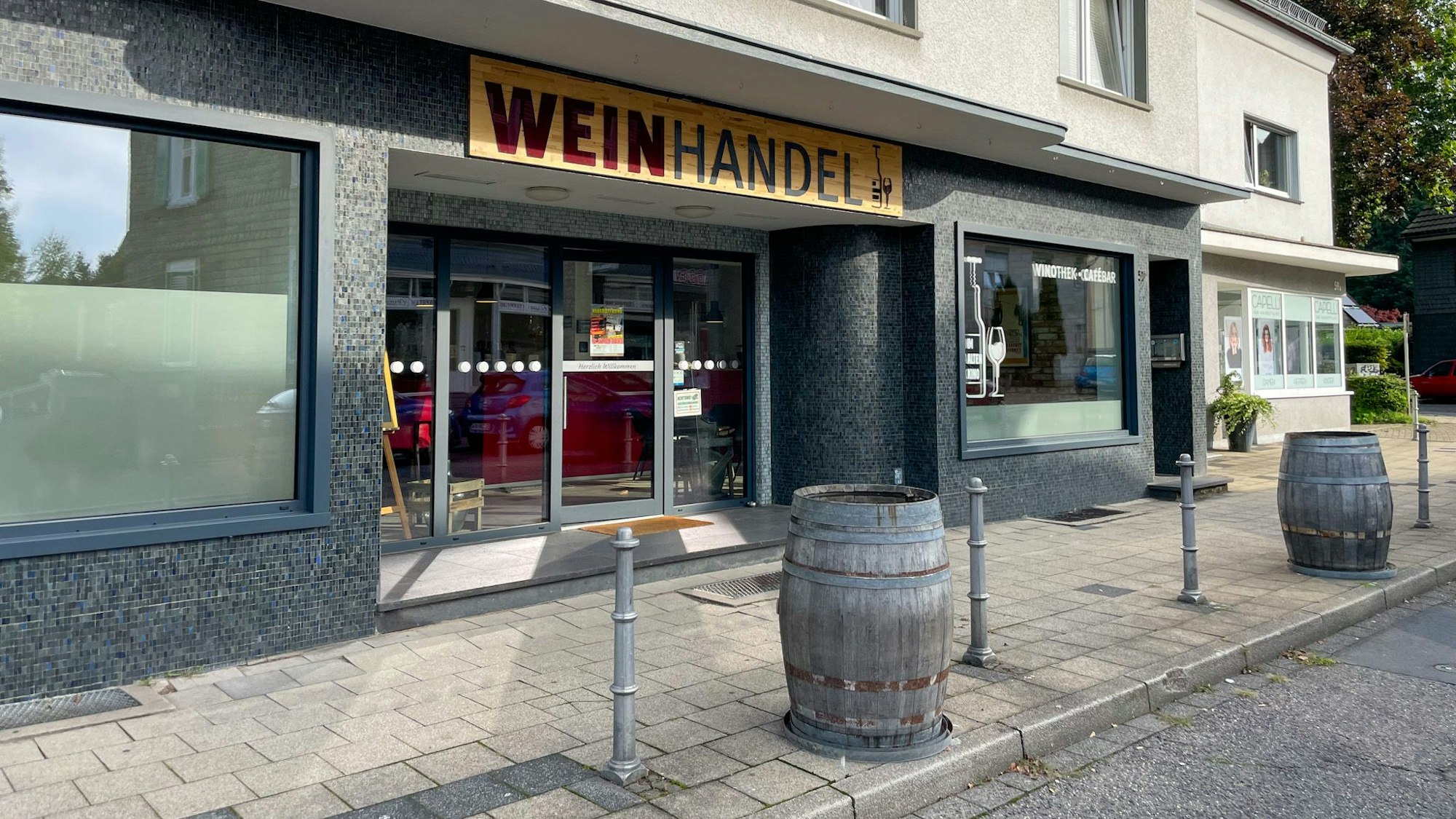 Der Weinhandel von außen, Fässer stehen auf dem Bürgersteig.