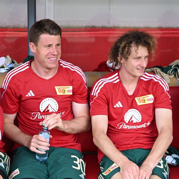 Dominique Heintz (l.) und Alex Kral sitzen bei einem Testspiel gegen Kiel auf der Bank von Union Berlin.
