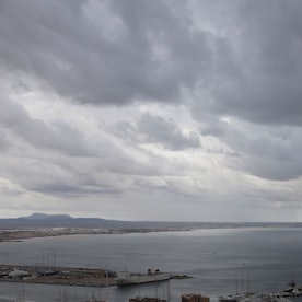 Dunkle Regenwolken hängen über der Bucht und einem Hafen auf Mallorca (Symbolbild).