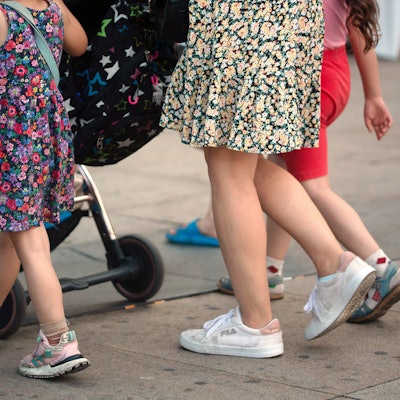 Eine Frau schiebt einen Kinderwagen und geht begleitet von mehreren Kindern. Die Ampel-Koalition hat sich beim Streitthema Kindergrundsicherung geeinigt.