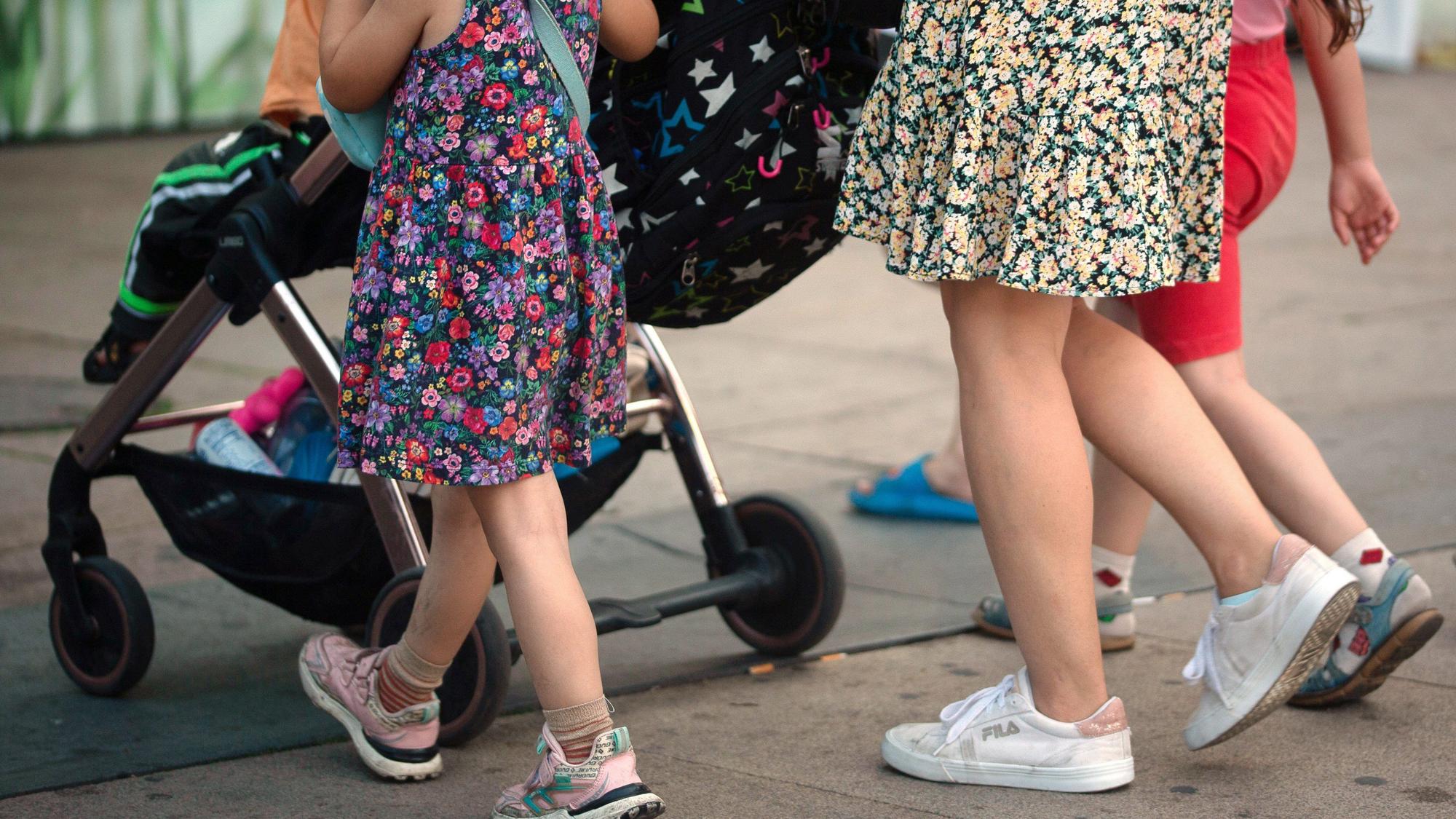 Eine Frau schiebt einen Kinderwagen und geht begleitet von mehreren Kindern. Die Ampel-Koalition hat sich beim Streitthema Kindergrundsicherung geeinigt.