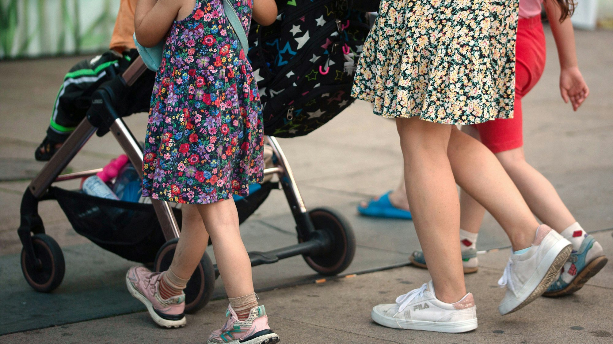 Eine Frau schiebt einen Kinderwagen und geht begleitet von mehreren Kindern. Die Ampel-Koalition hat sich beim Streitthema Kindergrundsicherung geeinigt.
