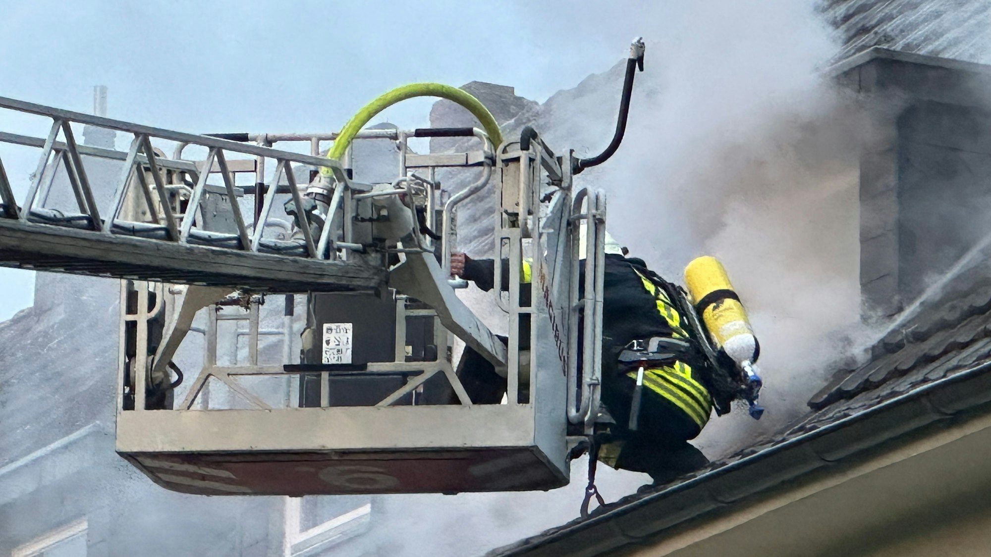 Eine Einsatzkraft der Feuerwehr auf dem Dach des Mehrfamilienhauses in Dünnwald.
