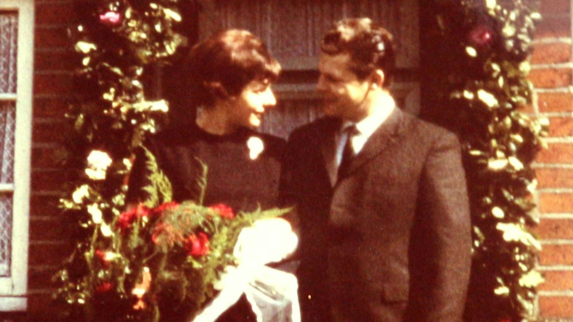 Eine Frau mit einem Blumenstrauß und ein Mann stehen nebeneinander und schauen sich an.