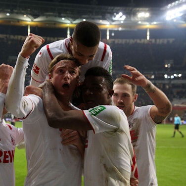 Spieler des 1. FC Köln umringen ihren Kollegen Sebastian Bornauw nach seinem Torerfolg. Einer springt ihm von hinten auf die Schultern.