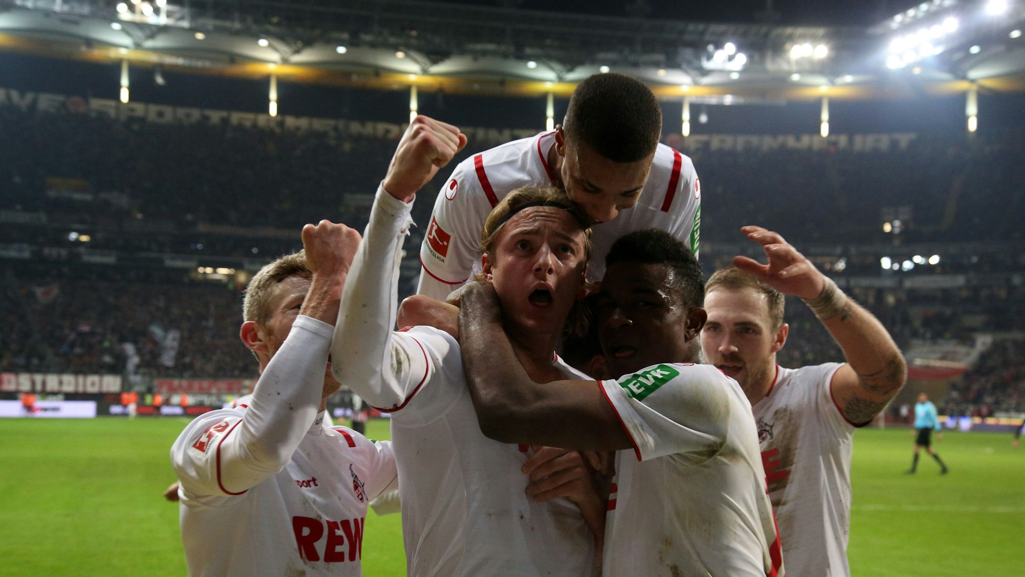 Spieler des 1. FC Köln umringen ihren Kollegen Sebastian Bornauw nach seinem Torerfolg. Einer springt ihm von hinten auf die Schultern.