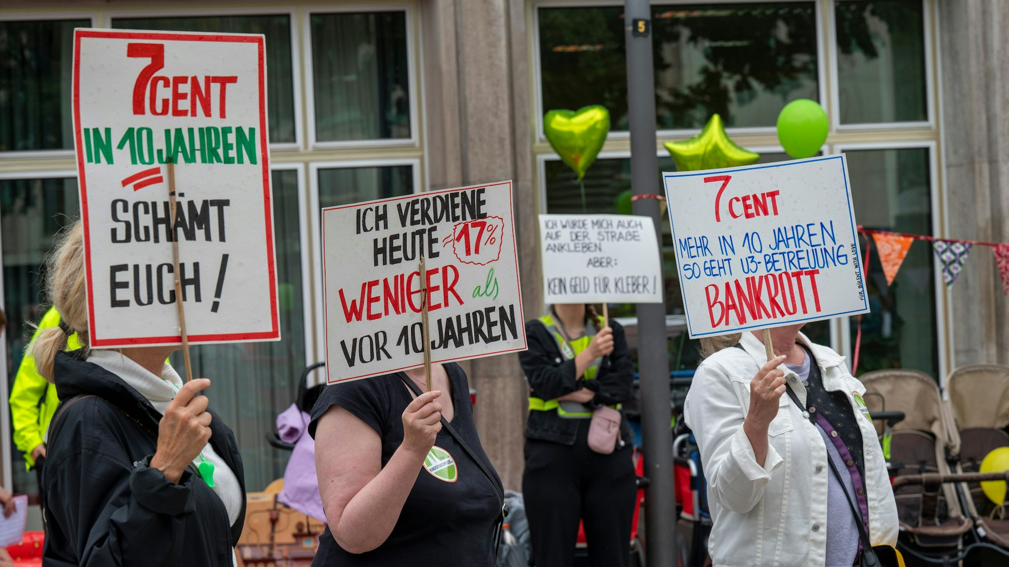 Das Bild zeigt Demonstrantinnen, die mit Schildern für den Erhalt der Kölner Kindertagespflege demonstrieren.