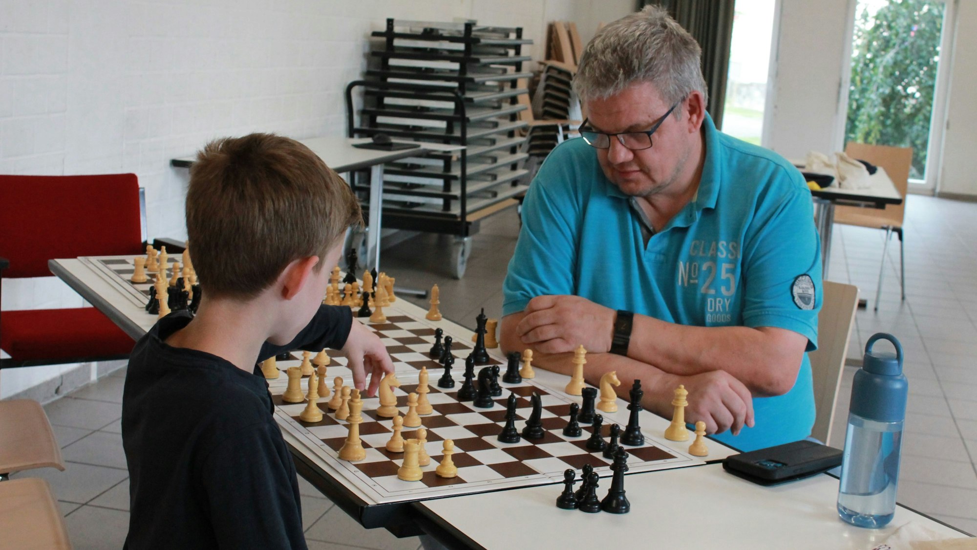 Ein Junge spielt gegen einen Mann Schach.